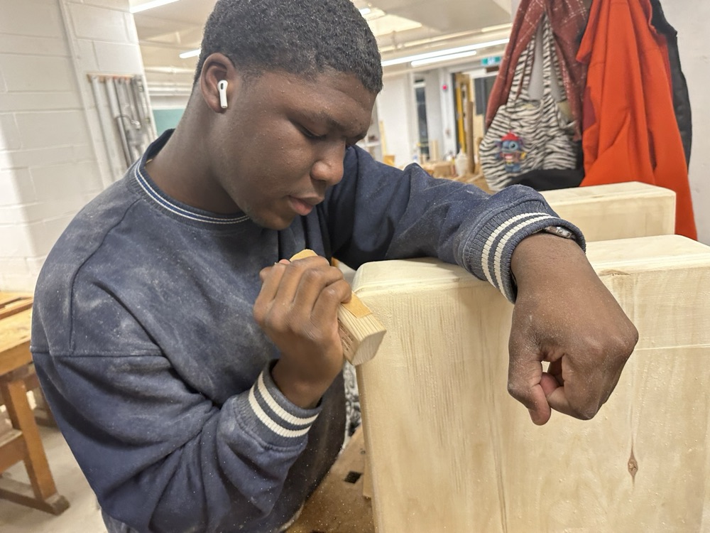 David hand-sanding one of the wooden blocks in the workshop