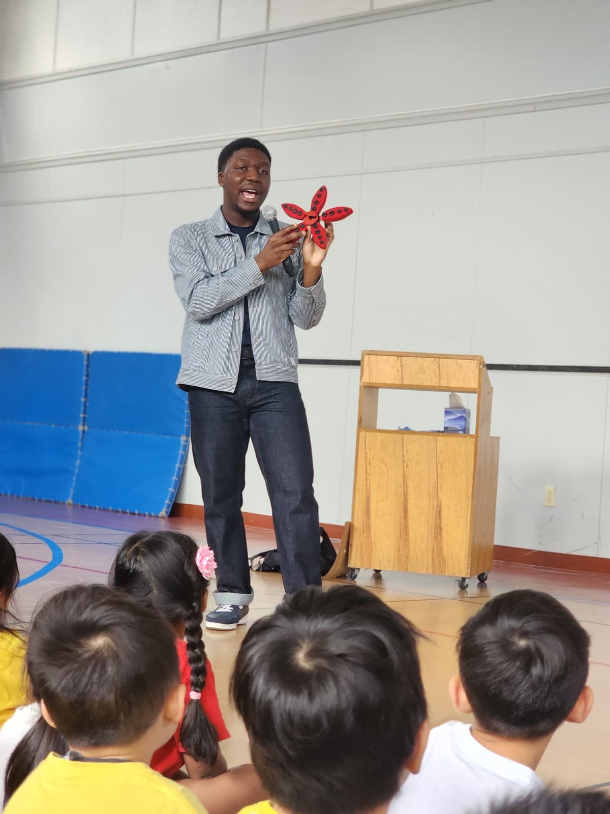 David presenting an invention to a school assembly of young children