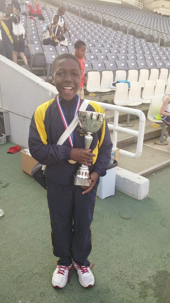 Young David smiling in an Olympic stadium, holding a trophy and wearing a gold medal